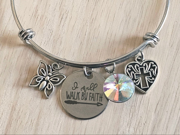 Silver bracelet with butterfly, heart, and round charm on a light wooden surface